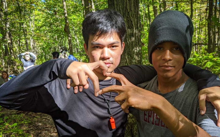 two teens make a heart using their hands while on a backpacking trip with outward bound
